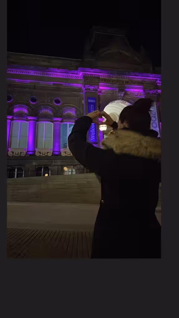 Woman facing a building lit up purple