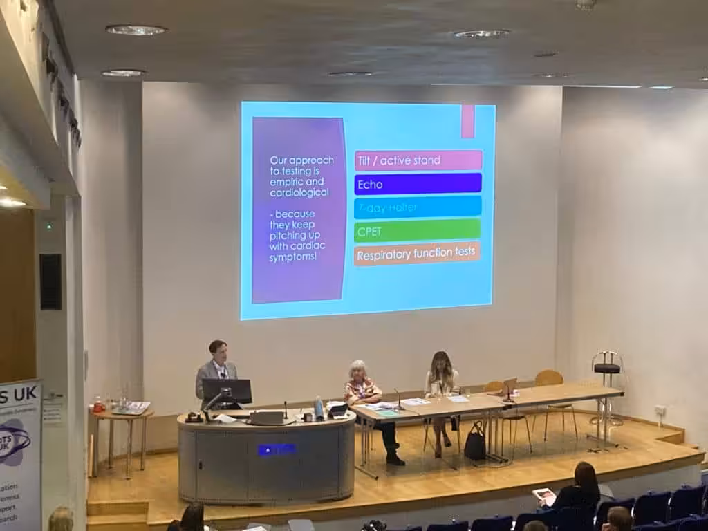 Male standing behind lectern presenting to a room of people for the PoTS and long covid masterclass