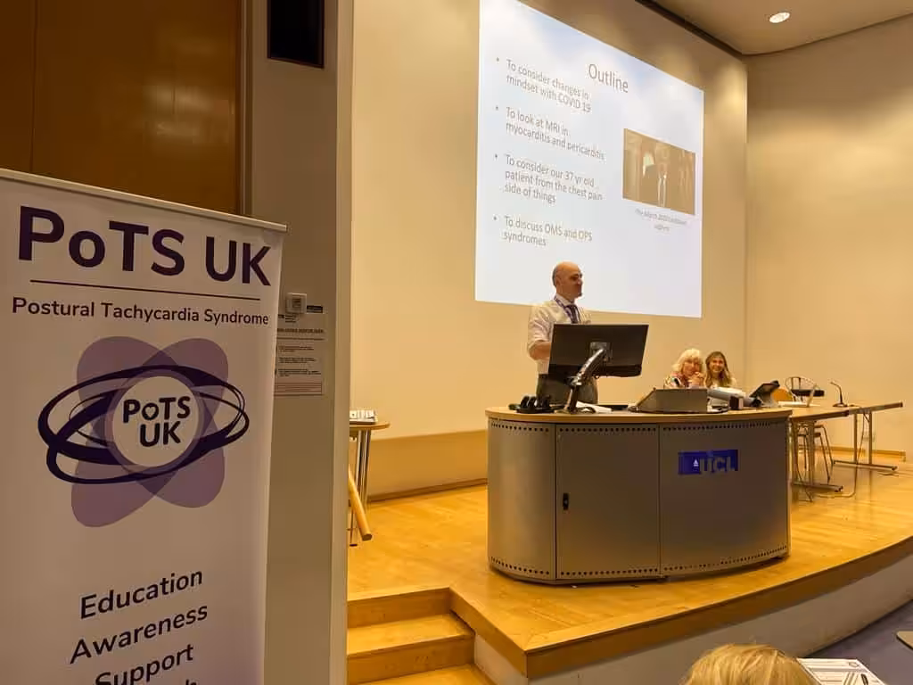 Male standing behind lectern presenting to a room of people for the PoTS and long covid masterclass