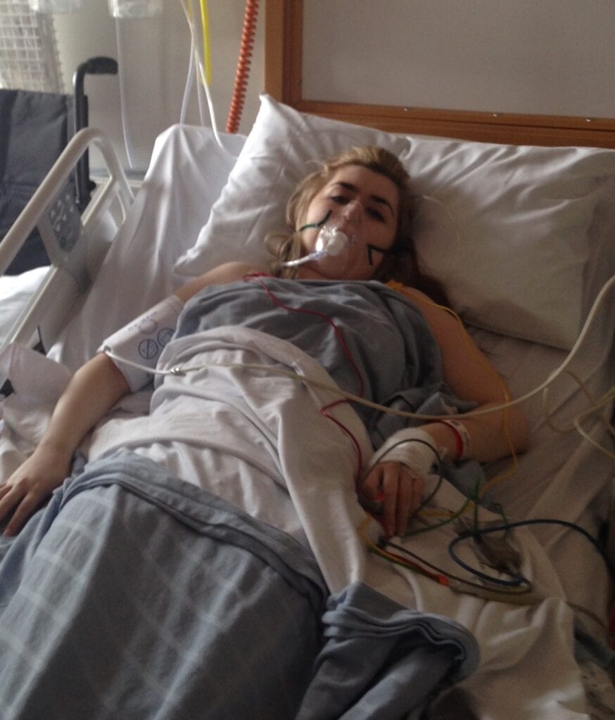Female lying in hospital bed with oxygen mask on