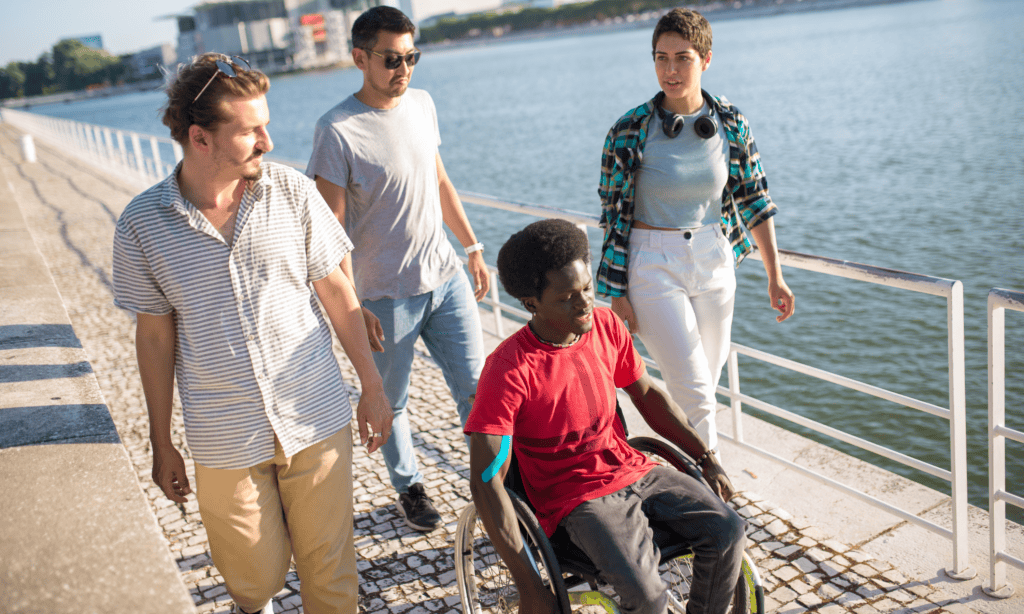 A male in a wheelchair, 2 males and females walking alongside