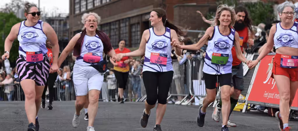 5 females running in PoTS UK vests whilst holding hands