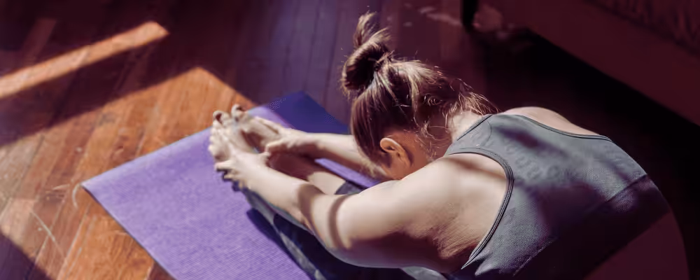 Yoga practitioner stretching on purple mat in bright room, promoting health and wellness with POTS UK awareness.